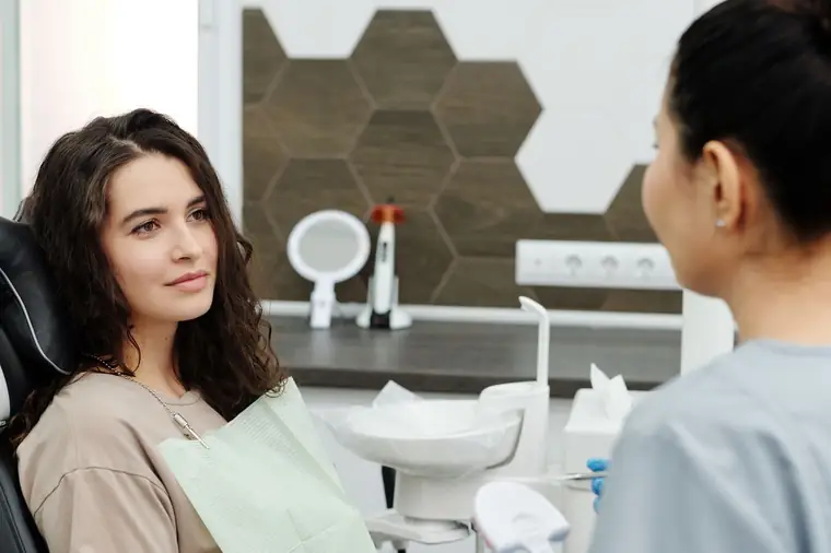 Dentista conversando com paciente na cadeira durante consulta de avaliação