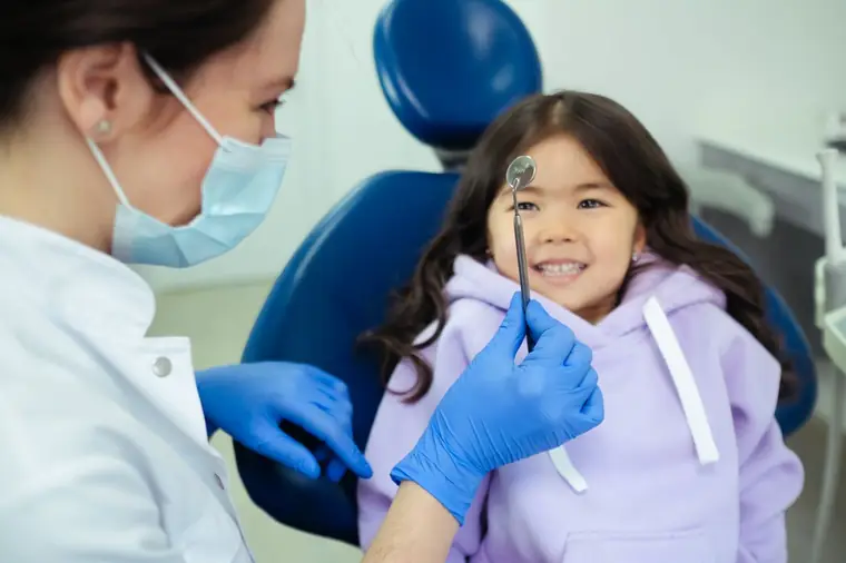 Criança sorrindo na cadeira do dentista durante atendimento infantil