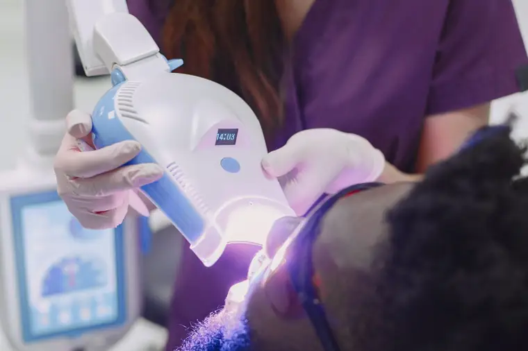 Dentista usando fotopolimerizador para finalizar uma restauração